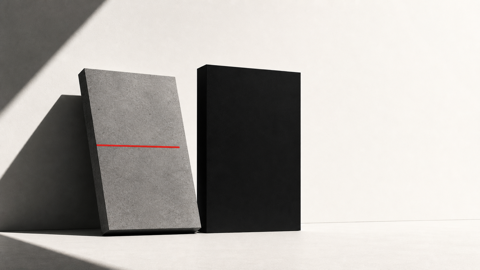 Two sculptural monoliths against an off-white ground: a grey concrete slab tilted forward in soft shadow, beside a black upright slab; a thin horizontal red line bisects them.